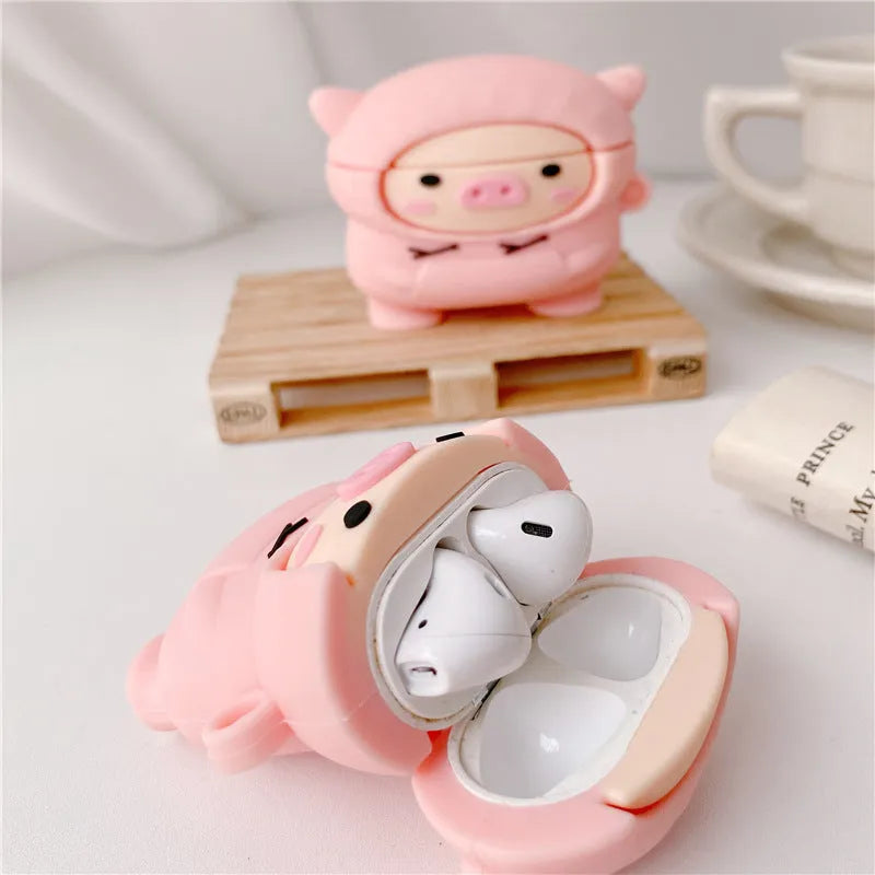 Pink silicone AirPods case with a cartoon pig in a sweater design and a silver keychain hook attached.