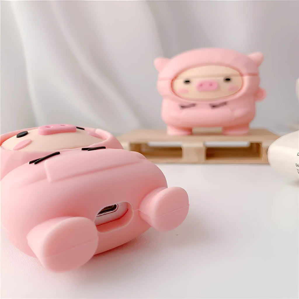 Pink silicone AirPods case with a cartoon pig in a sweater design and a silver keychain hook attached.