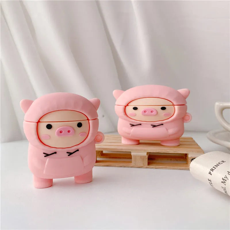 Pink silicone AirPods case with a cartoon pig in a sweater design and a silver keychain hook attached.