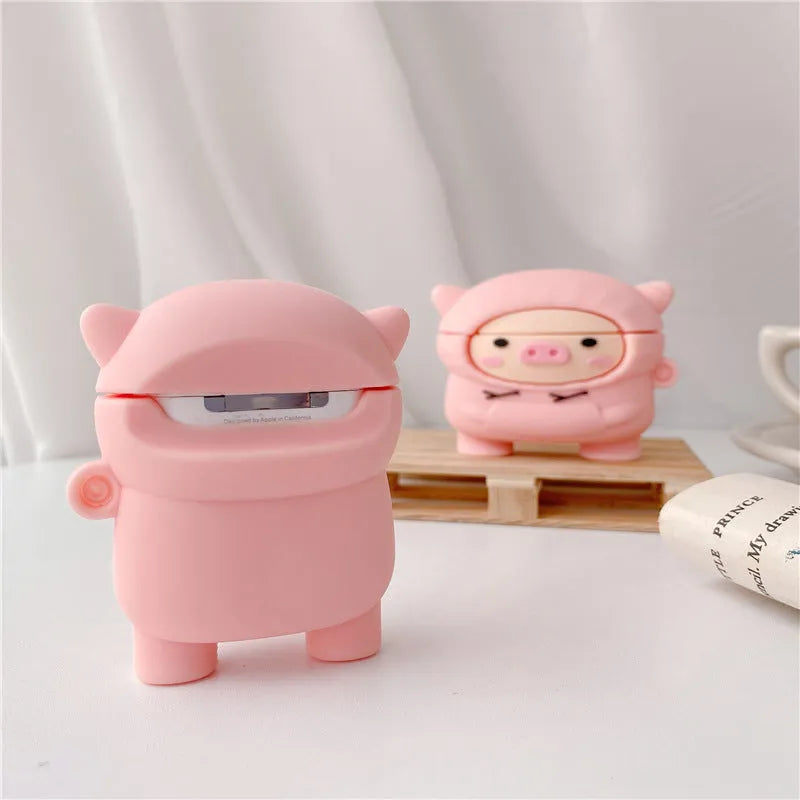 Pink silicone AirPods case with a cartoon pig in a sweater design and a silver keychain hook attached.