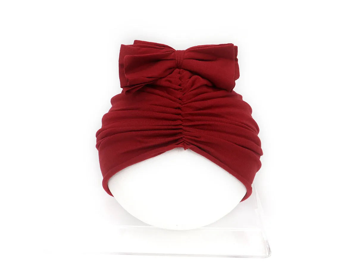 Soft knitted acrylic baby bonnet headwrap for girls in a range of candy colours, fitting 0-28 months.