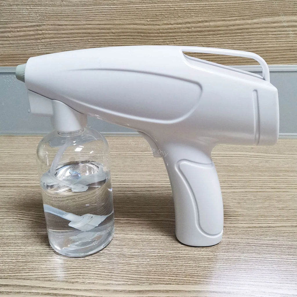 White handheld cordless electric spray disinfection gun with USB charging cable.