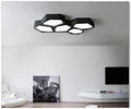 Geometric shaped black iron LED wall light with remote control on a living room wall.