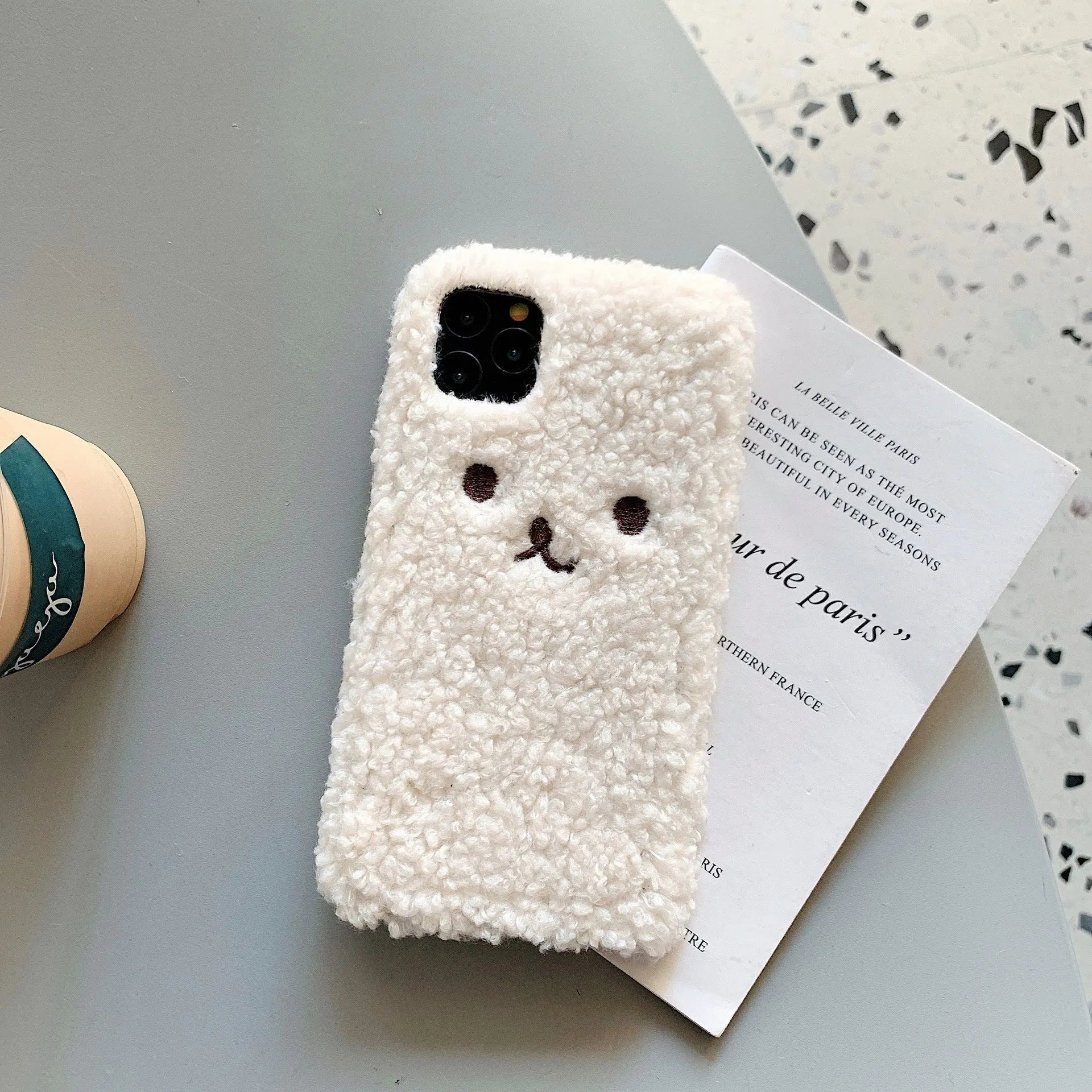 Brown and white embroidery plush cartoon bear face design on a flexible TPU iPhone case.