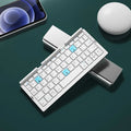 Silver folding Bluetooth keyboard open with phone standing in integrated holder