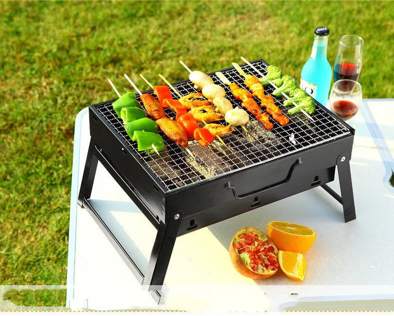 Folding portable charcoal barbecue grill on outdoor table showing 35x27x20cm cooking area