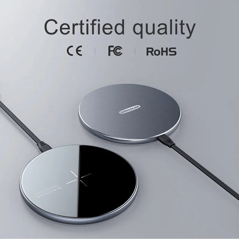Black MagSlim magnetic wireless charging pad on a table next to a mobile phone.
