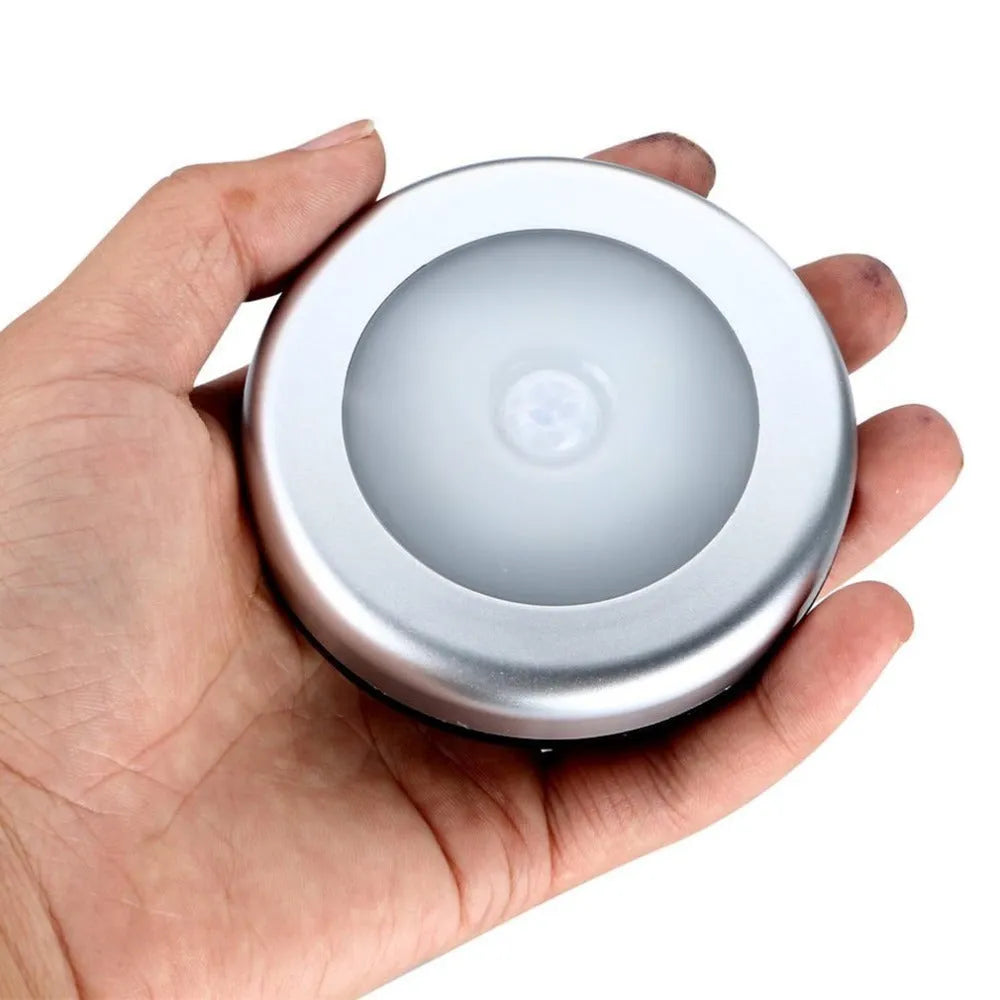 Silver wireless motion sensor night light with a square 80mm design on a table.