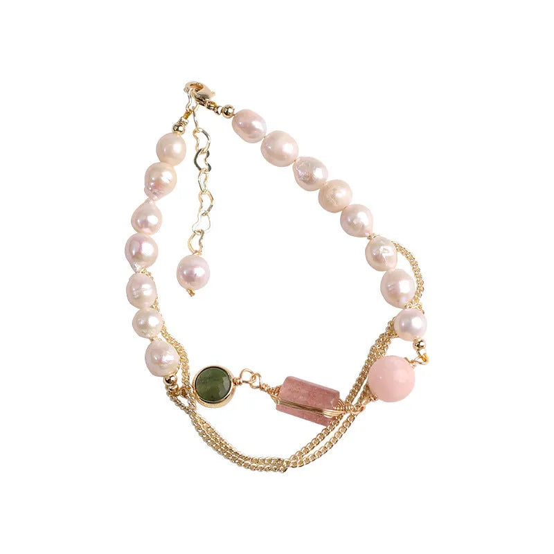 Close-up of a pink freshwater pearl bracelet with strawberry-shaped crystal charms on a geometric model.