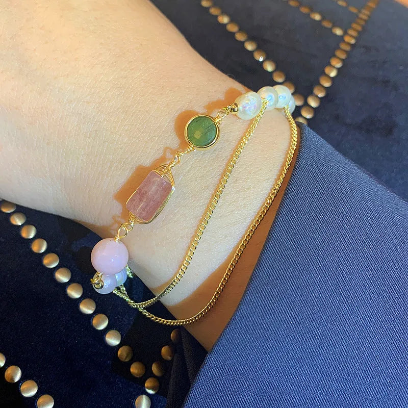 Close-up of a pink freshwater pearl bracelet with strawberry-shaped crystal charms on a geometric model.