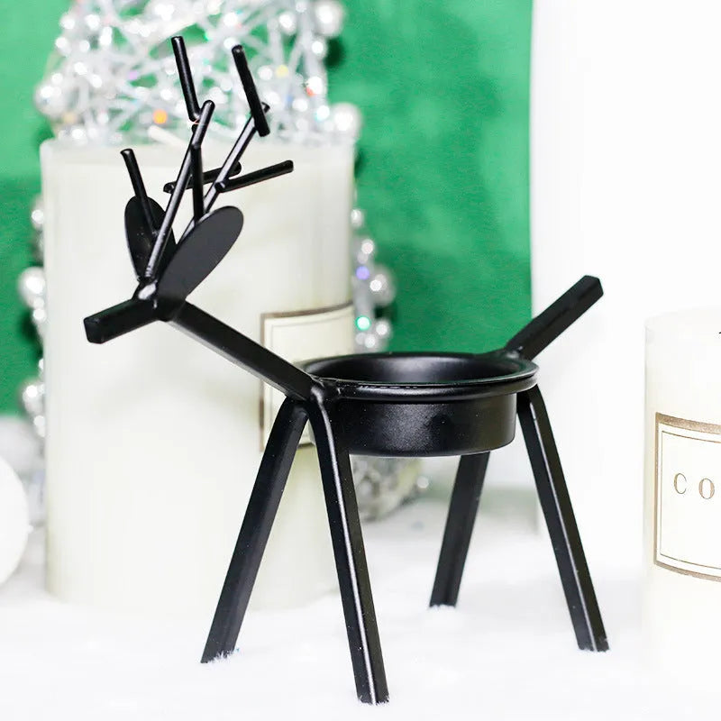 Black iron Christmas candlestick holder with decorative elk design on a festive table.