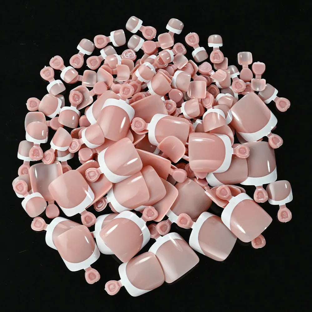 Box of 120 short square false toenails with French white tip design on nude base.
