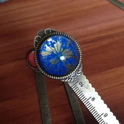 Handmade dried flower bookmark ruler with gypsophila, lace flowers, and clover, 12cm long on a book page.