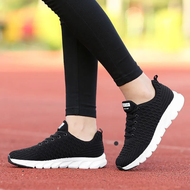 Women's running shoes in black, pink, or white with a fly weave upper and durable outsole.