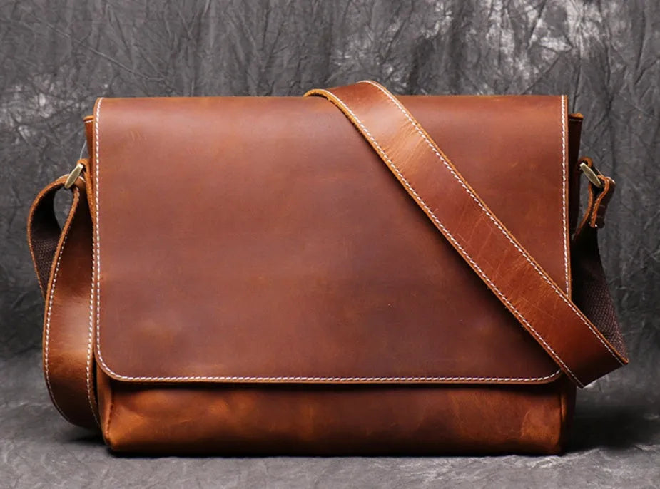 Vintage brown men's leather messenger bag showing interior compartments and adjustable shoulder strap