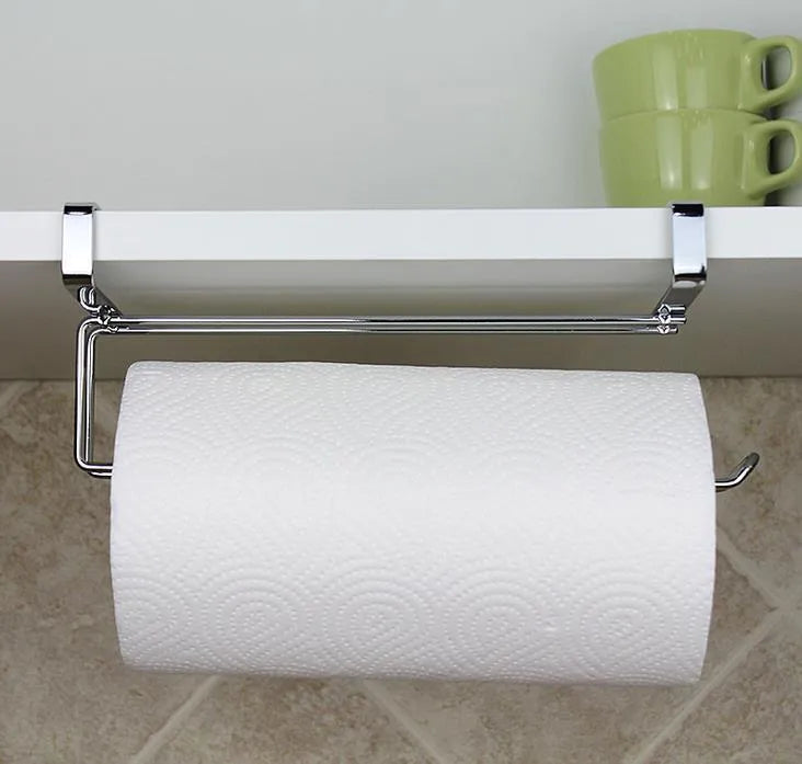 Silver stainless steel paper towel rack hanging on a kitchen cabinet door