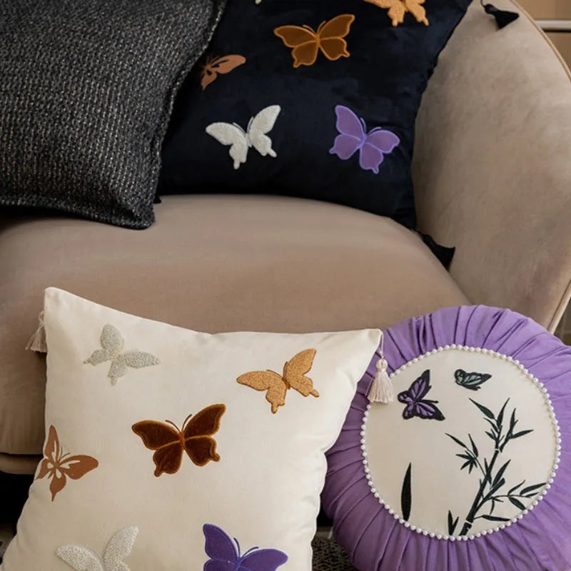 Square beige cushion with detailed purple and black butterfly embroidery in a Chinese floral pattern.