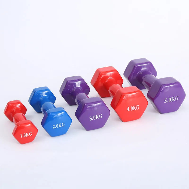 Bright green and pink plastic fitness dumbbells with glossy finish on a wooden floor.