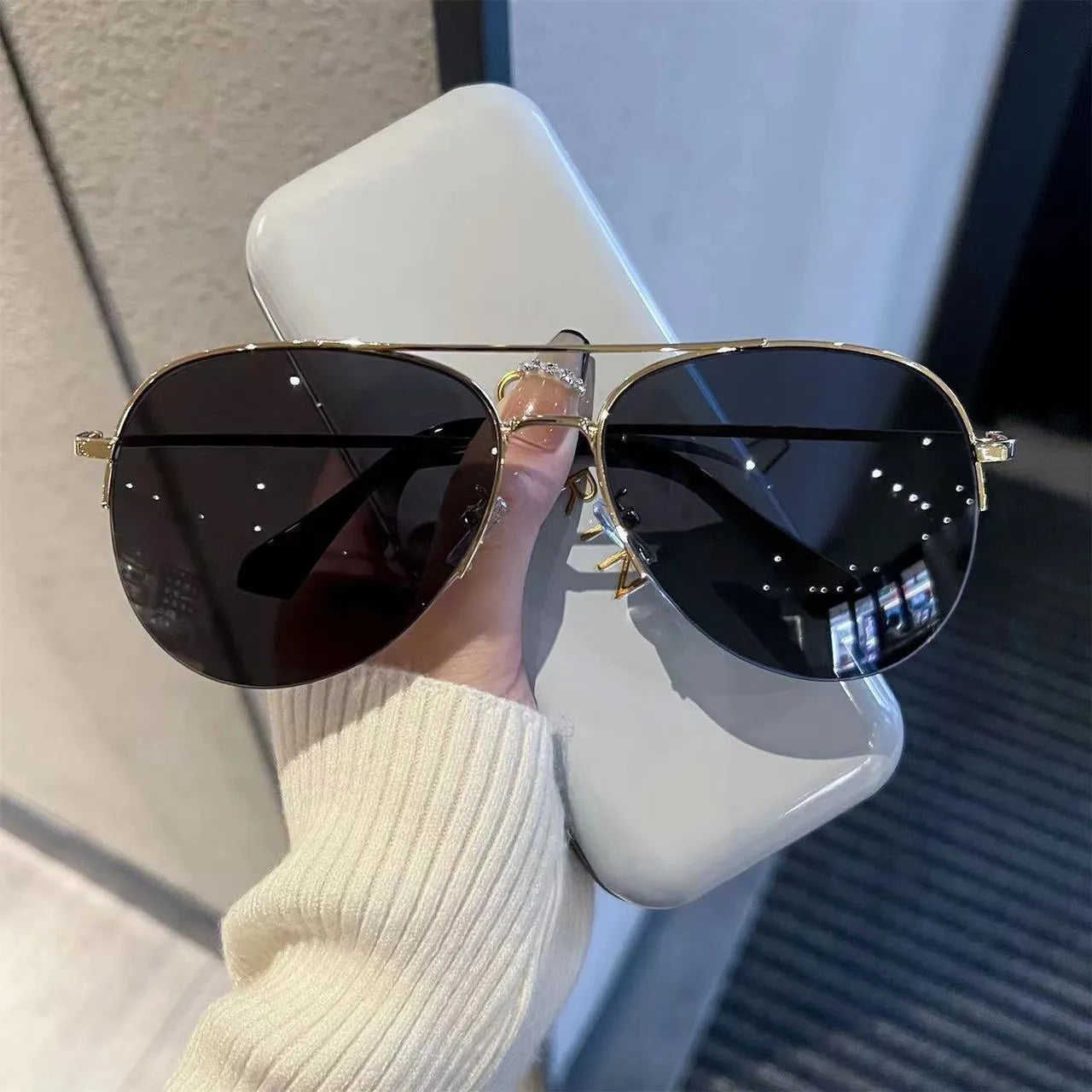 Aviator-style sunglasses with a metal frame and tinted resin lens, shown in a gold frame variant.