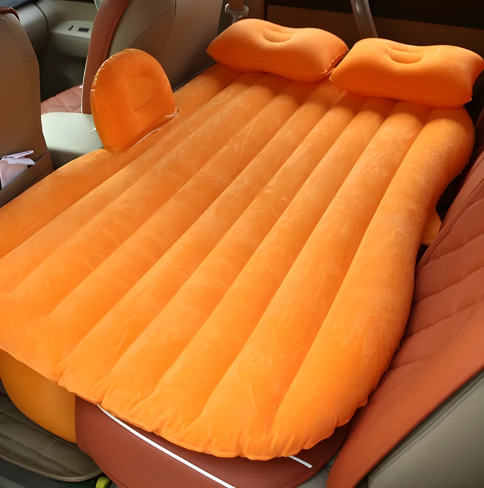 Inflatable car bed with flocked surface folded beside storage bag and two pillows