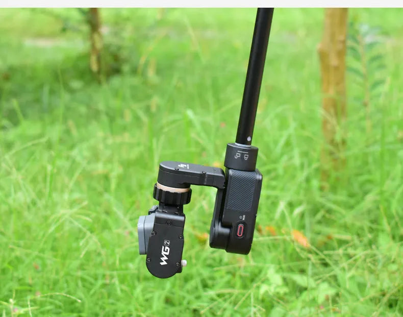 Black retractable selfie stick extended fully with phone attached, showing stabiliser grip.