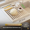 Foldable milky white stainless steel kitchen draining rack with dishes, shown next to a sink.