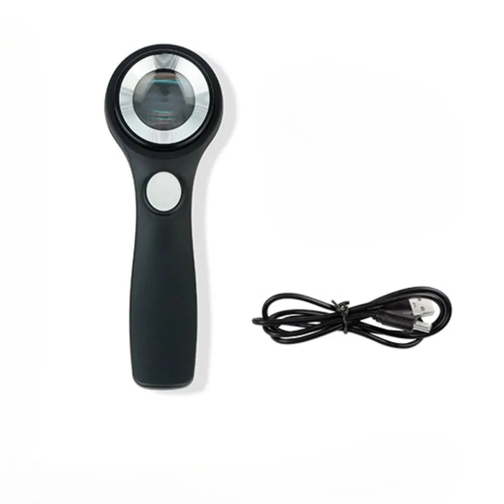 Black and silver handheld appraisal magnifying glass with optical glass lens and USB-C cable on a table.