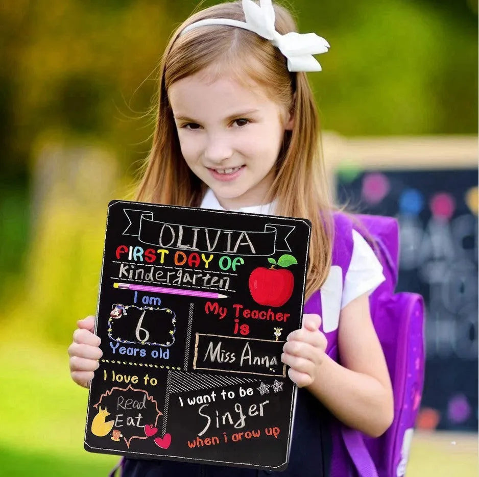 Wooden first day of school blackboard sign on a simple background.
