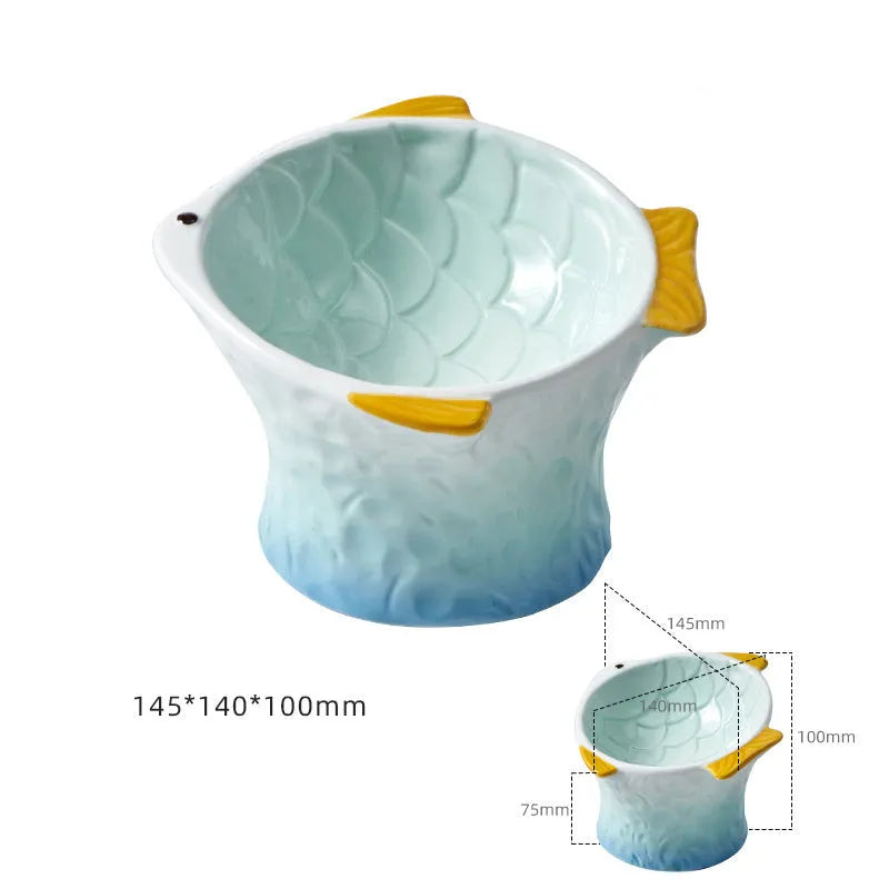 Blue ceramic cat food bowl in a fish shape with a tilted, elevated design and non-slip base.