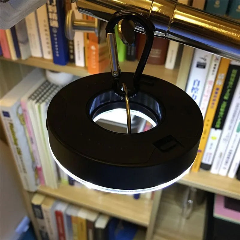 Primary colour COB LED tent light with carabiner hook and transparent lampshade on a dark background