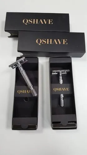 Double edged safety razor with metal handle and head next to its blade and storage box.