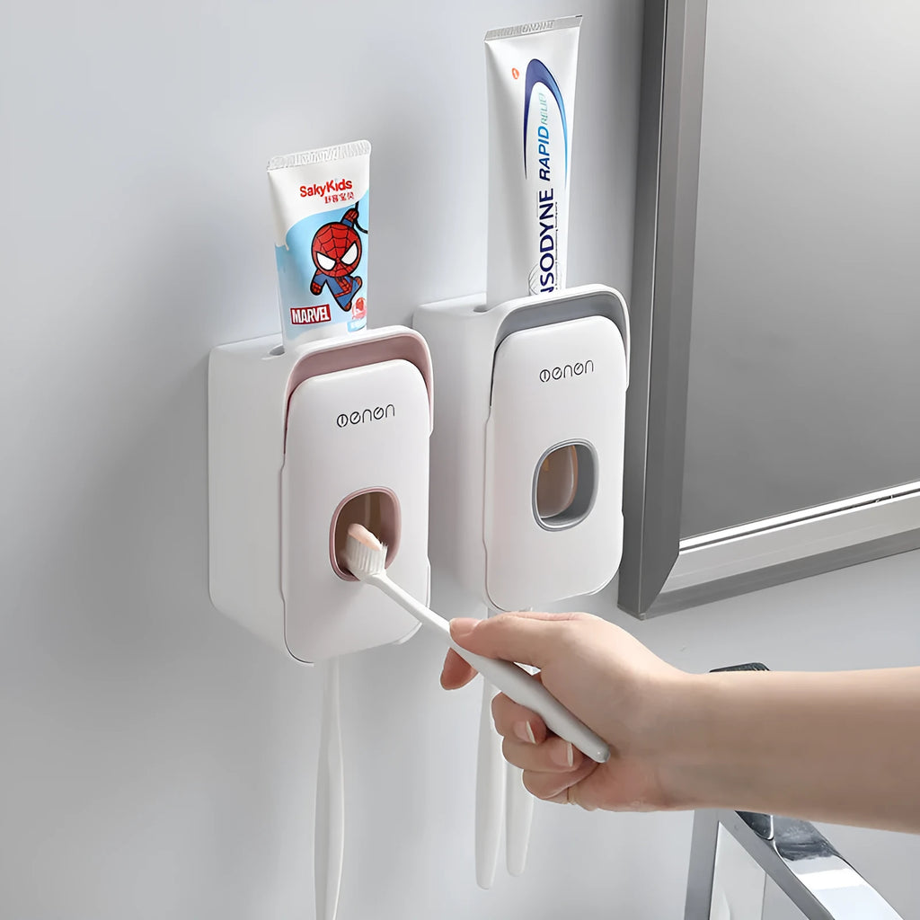 Wall-mounted automatic toothpaste dispenser in blue, grey, or pink colours with a visible dispensing lever.