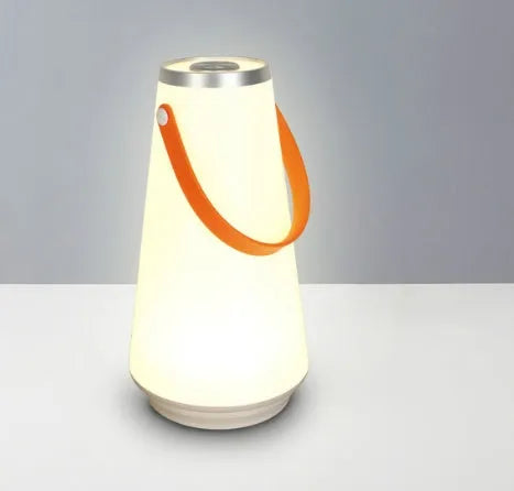 White rechargeable LED bedside lantern with USB cable on a table.