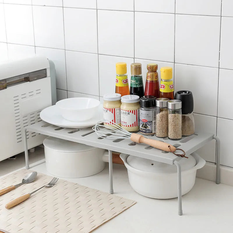 White telescopic plastic kitchen rack extended to 69cm height on kitchen countertop