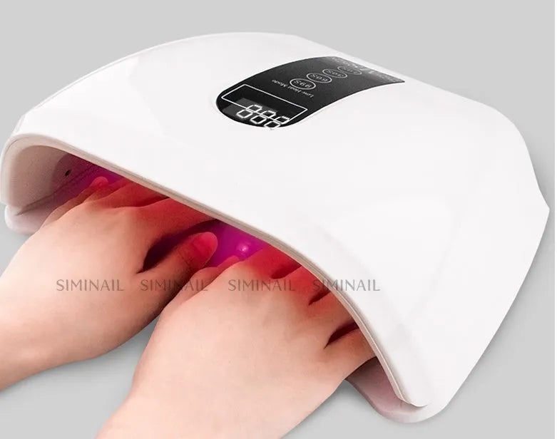 White 96W LED nail dryer with red light, 48 lamp beads, and removal base tray on a desk
