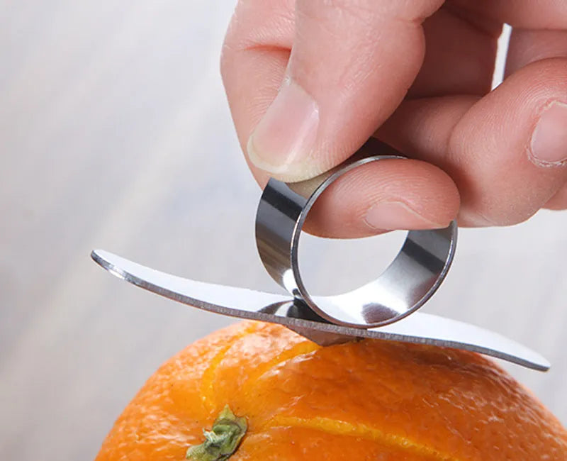 Stainless steel ring orange peeler on a countertop with citrus fruits nearby, showing compact silver tool