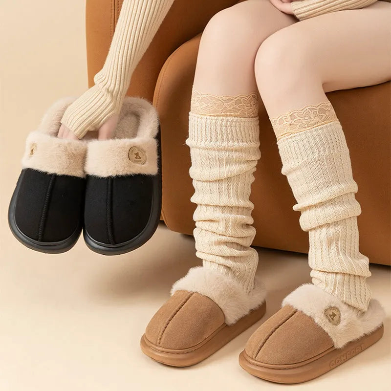 Pair of plush fleece slippers with textured PVC sole and cross stitching detail.
