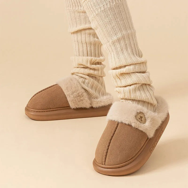 Pair of plush fleece slippers with textured PVC sole and cross stitching detail.