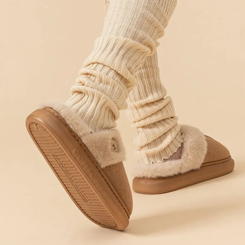 Pair of plush fleece slippers with textured PVC sole and cross stitching detail.