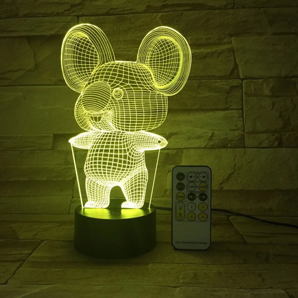 Black koala night light with colourful LED glow on a small table, showing remote control.