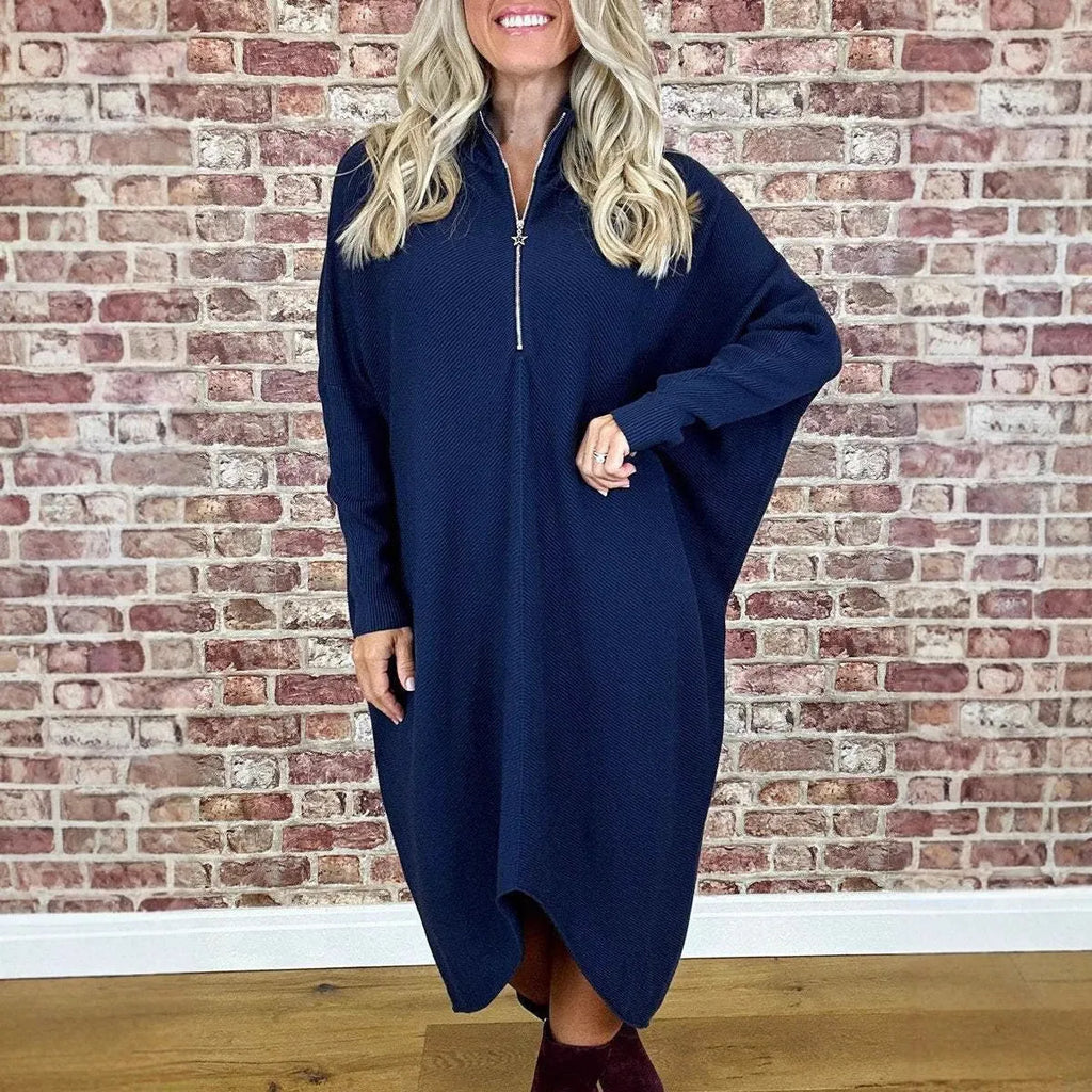 A woman wearing a loose-fitting solid colour knitted dress with raglan sleeves and a front zipper.