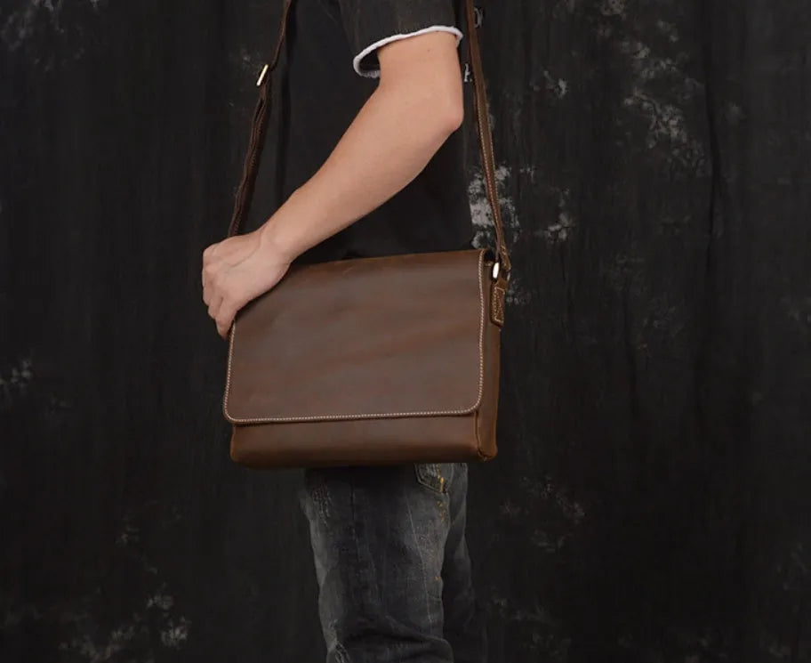 Vintage brown men's leather messenger bag showing interior compartments and adjustable shoulder strap