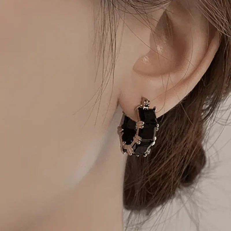 Geometric U-shaped gold tone earrings with round black zircon stone.