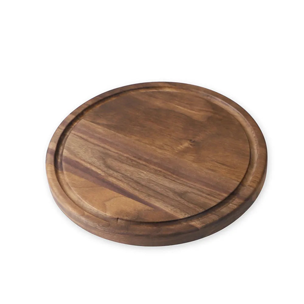 Black walnut wood cutting board with sauce groove and carved side handle on kitchen counter