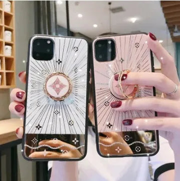 Rose gold diamond-shaped ring stand attached to the back of an iPhone, acting as a grip and phone stand.