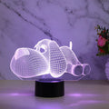 Doggo desktop lamp with 3D illusion design glowing in multiple colours on a desk.