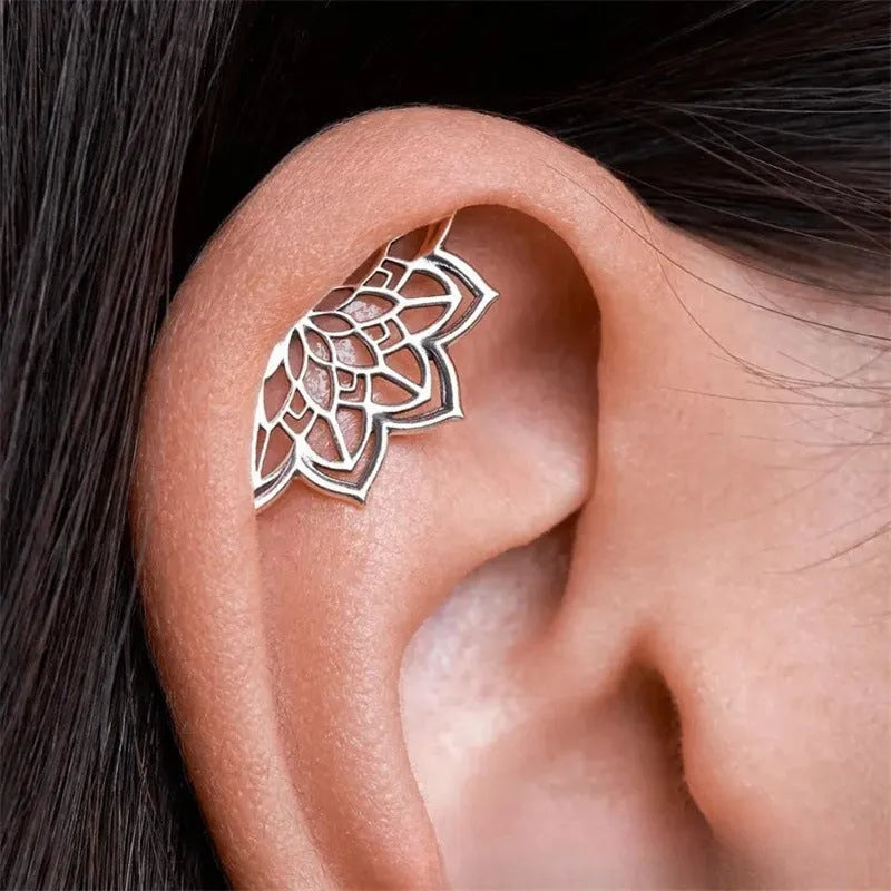 Close-up of geometric spider web patterned metal stud earrings in a gold electroplated finish.