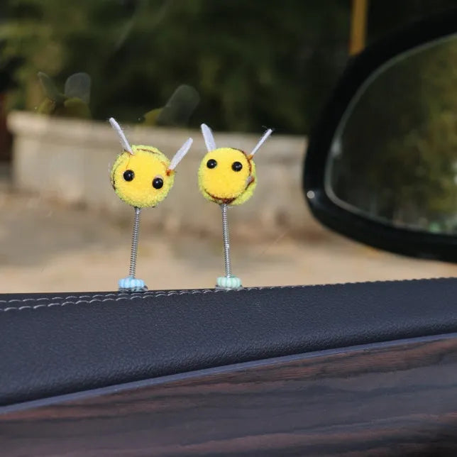 Small, soft, cartoon bee car decoration made from yellow and black fur ball material.