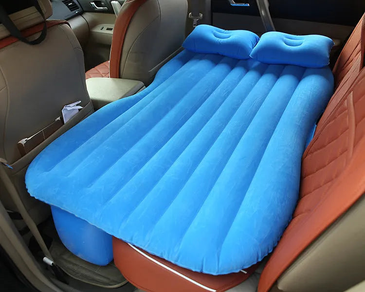 Inflatable car bed with flocked surface folded beside storage bag and two pillows