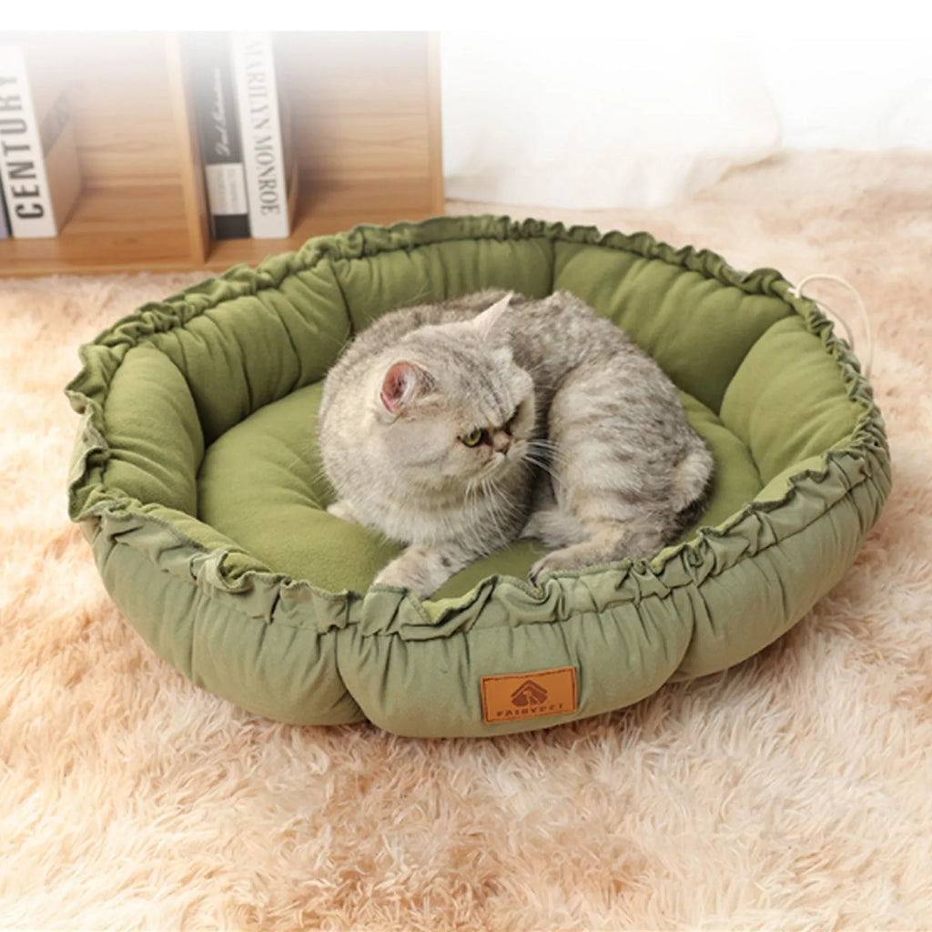 Grey reversible donut-shaped cat bed for indoor pets on a wooden floor.